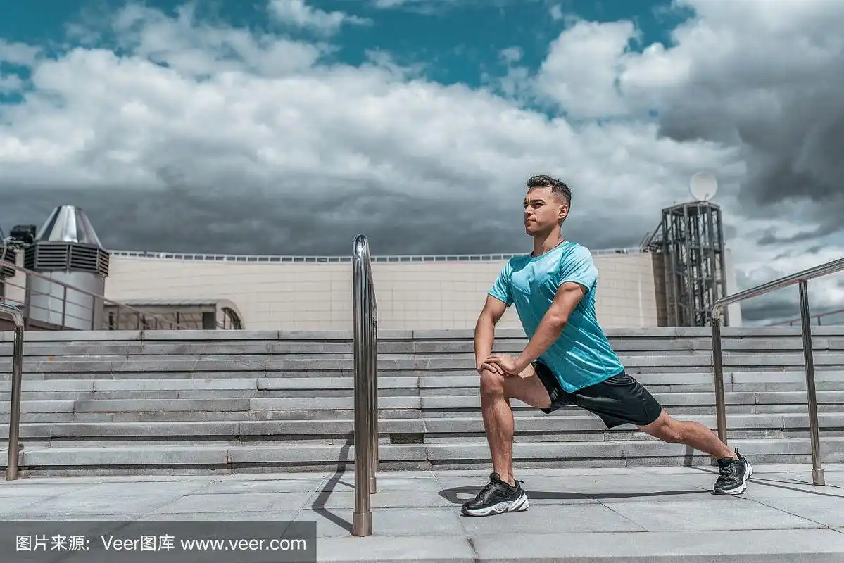 一名男性运动员在夏季做弓步运动,在慢跑前拉伸肌肉,进行健身训练,穿