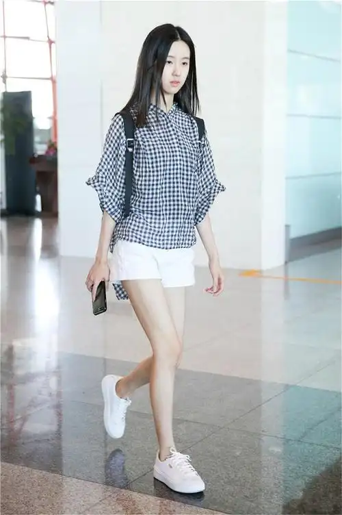 近日,"国民校花"陈都灵现身机场,黑白格衬衫搭配白色牛仔短裤,素颜