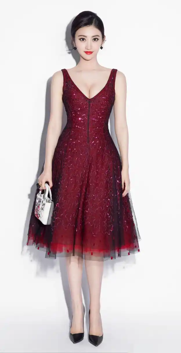 在浓郁的酒红色裙装的衬托下,她的皮肤雪白,根本就不需要打光,美成了