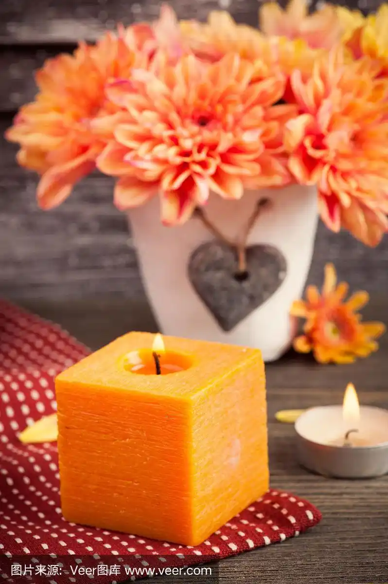 橙色菊花和点燃的蜡烛