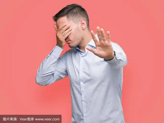 英俊的年轻商人用手捂着眼睛,做着停顿的手势,带着悲伤和恐惧的表情.