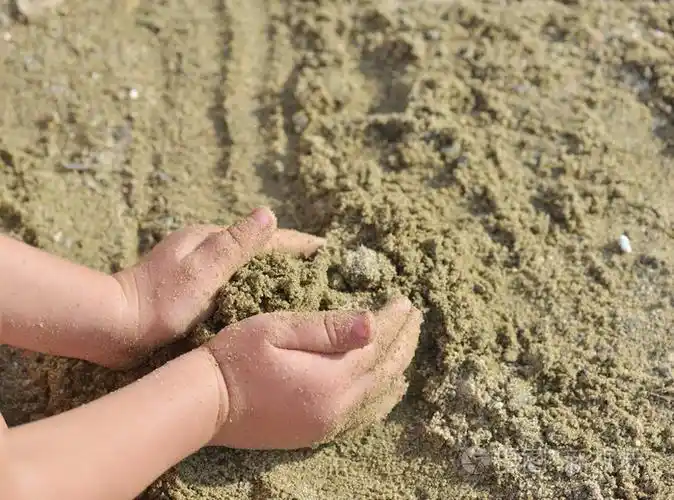 日落时孩子们在海滩上玩沙子开始建造一座城堡
