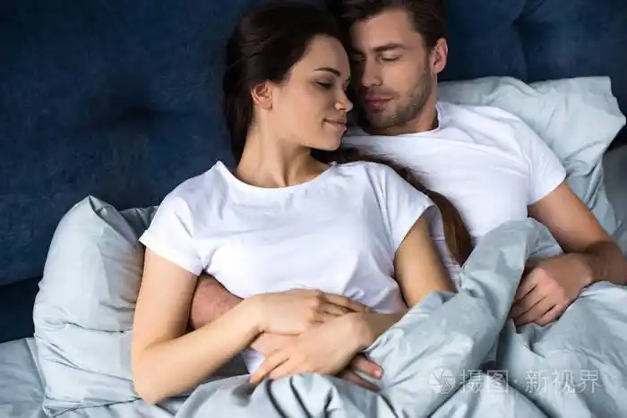 胡子男人拥抱有魅力的黑发妻子在床上