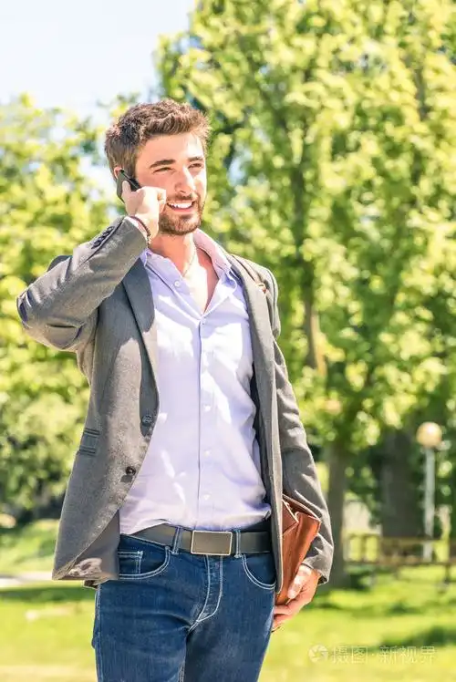 年轻商人在公园与智能手机休息后工作日发短信-现代混合与人类的城市