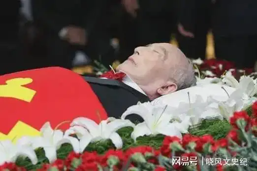 照片中的他躺在鲜花丛中,身上盖着一面党旗,遗容非常的安详,他身穿