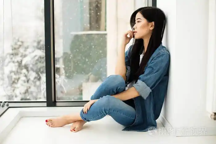 亚洲女孩坐在地板上的窗边