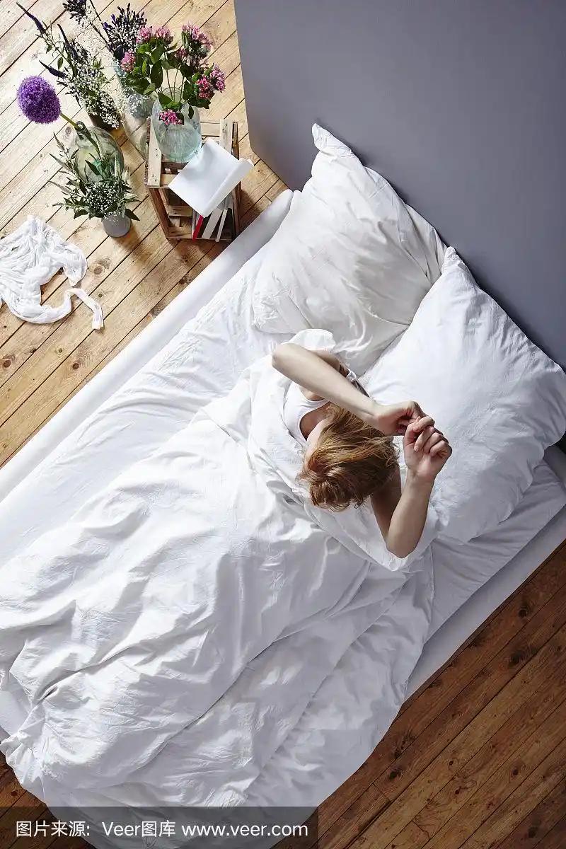 年轻女子从床上伸懒腰醒来