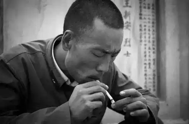 烈士陵园,一名参战老兵在自己牺牲的战友墓前抽着闷烟.