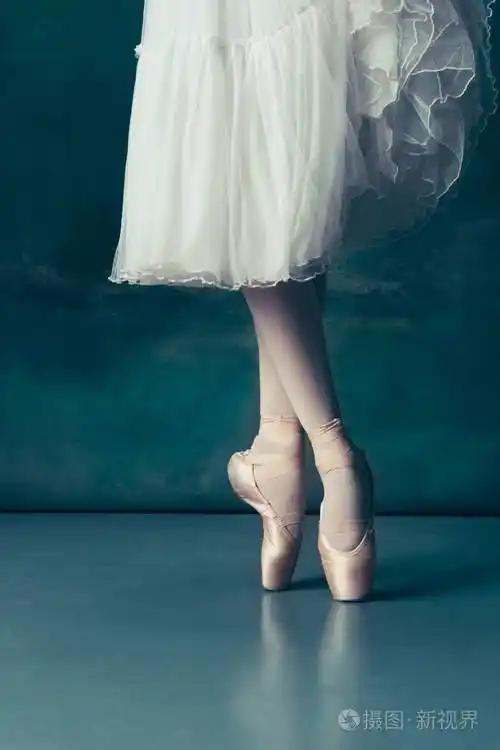 灰色木地板上指出的特写芭蕾舞腿
