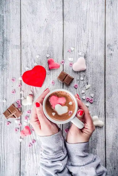 女孩手拿热巧克力棉花糖心红粉白色巧克力片糖洒旧木背景复制空间顶部