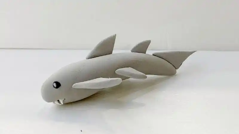 2,接着依次在背部捏几个鱼鳍粘在上面,左右两边也有两个略大的鱼鳍.