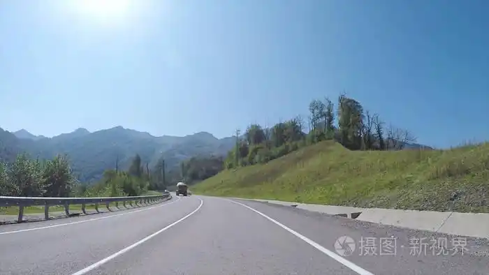 汽车在蜿蜒的高速公路上向前行驶,四周是森林覆盖的山丘,驾驶员视野