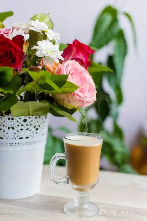一杯热咖啡与牛奶站在窗边, 一束鲜艳的花