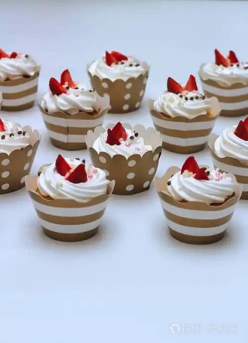 特写纸杯蛋糕与生鸡蛋奶油装饰新鲜草莓和巧克力球在白色背景隔离