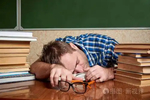 精疲力竭的年轻人睡在一张桌子上,桌子上放着一堆书.
