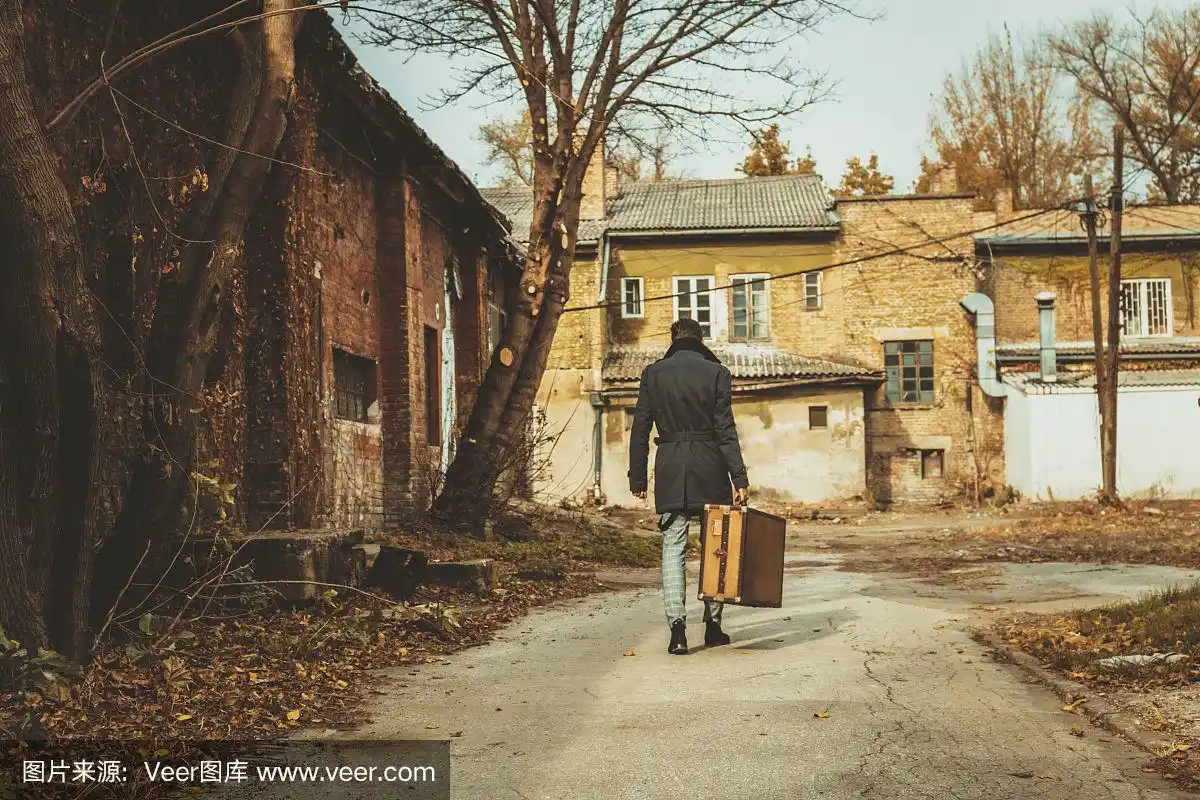 一个男人提着箱子离开的背影.