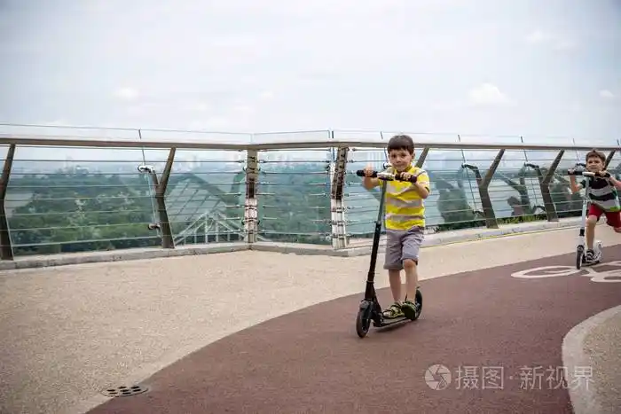 男孩在当地公园里骑着他的滑板车阳光明媚的夏天