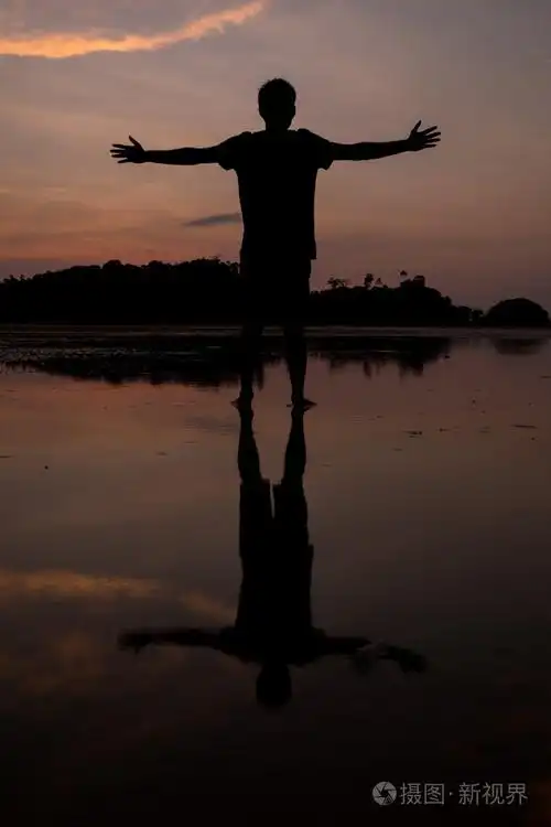 与水中倒影在日落海滩上的人