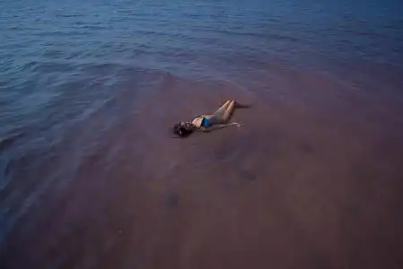 一个穿着蓝色比基尼的女人在盐湖里仰面游泳.大自然的奇迹粉红湖.