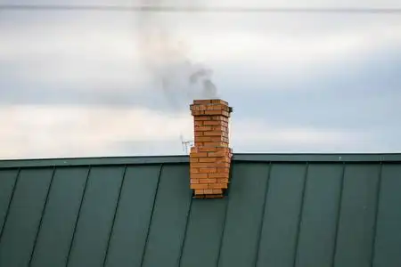 浓烟滚滚.从一个房子的烟囱里出来,背景是蓝天照片