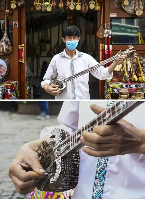 下图为5月1日,艾尔肯弹奏热瓦甫(一种维吾尔族传统乐器)招徕游人