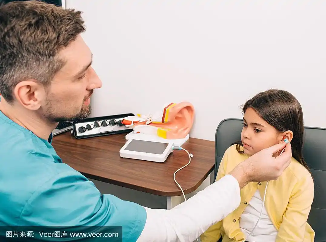 听力学家检查孩子的耳朵.混血女孩在做听力测试,阻抗测听