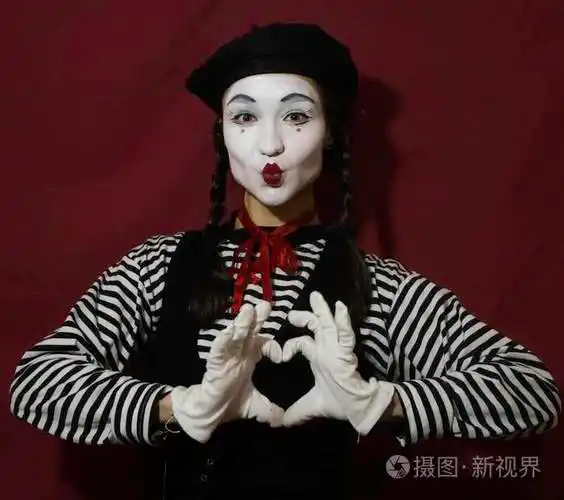 一个美丽的女孩在一个哑剧演员的形象从她的手折叠一个心脏看照相机.