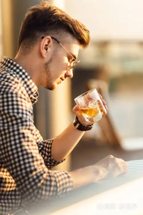 时尚的男人坐在表和喝威士忌