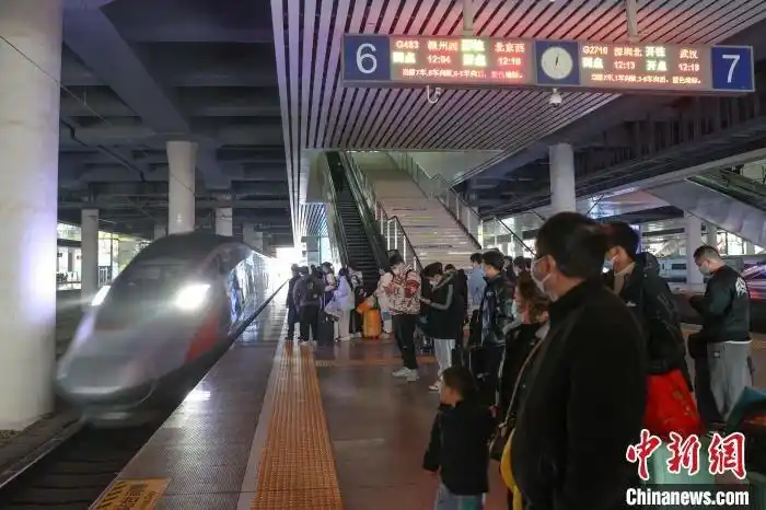 图为江西南昌西站,一辆高铁列车进站,旅客在站台上排队候车.