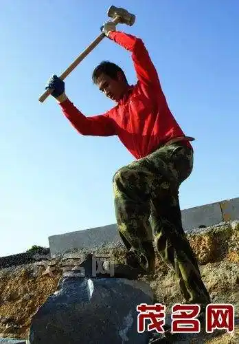 工人在深茂铁路工地抡起大锤砸石头.