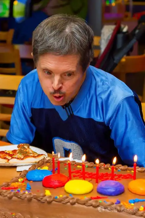 一个有唐氏综合症的老人在他的生日蛋糕上用蜡烛吹熄了他的礼物.