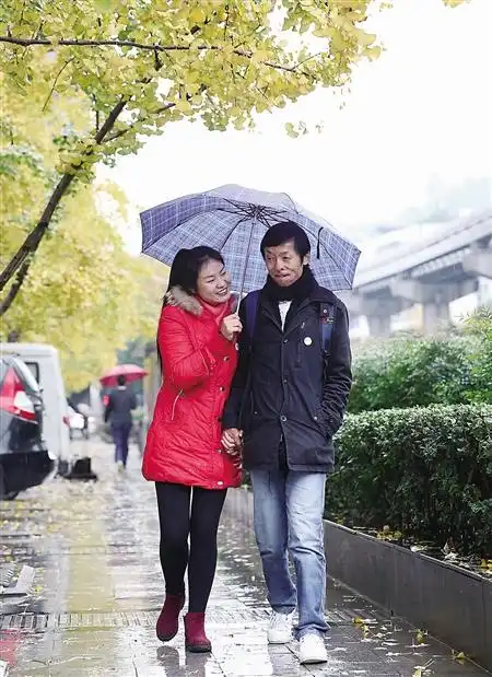 昨日,殷建行与妻子手牵手在雨中漫步.