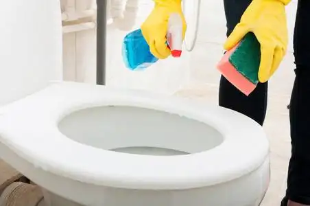 用橡胶手套的女人清洗马桶照片