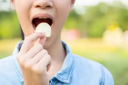 垃圾食物上瘾特写,糟糕的食物,亚洲小女孩吃薯片,年轻女子把薯片薯片