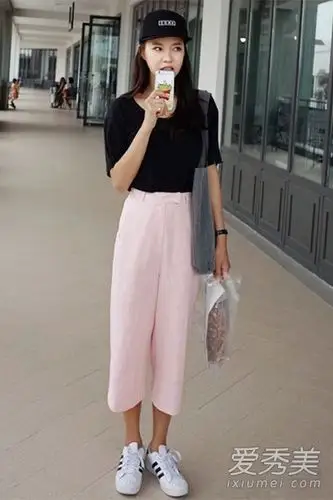 黑色短袖t恤搭配浅粉色阔腿裤,穿上白色球鞋,背着深色肩挎包,休闲大方