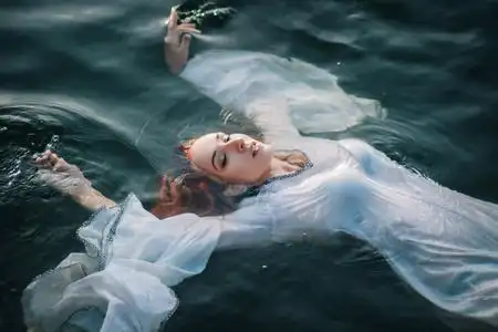 美丽的红头发的女孩漂浮在水中.洛基海岸.