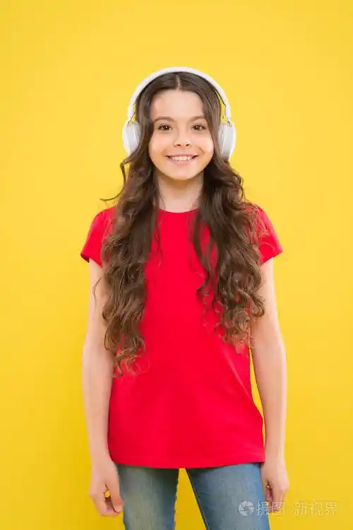 可爱的女孩喜欢黄色背景音乐.小孩子用立体声耳机听音乐.幼儿音乐教育