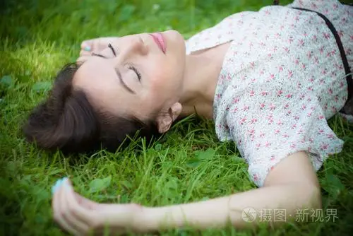 年轻女子躺在草地上照片-正版商用图片1ewaws-摄图新视界