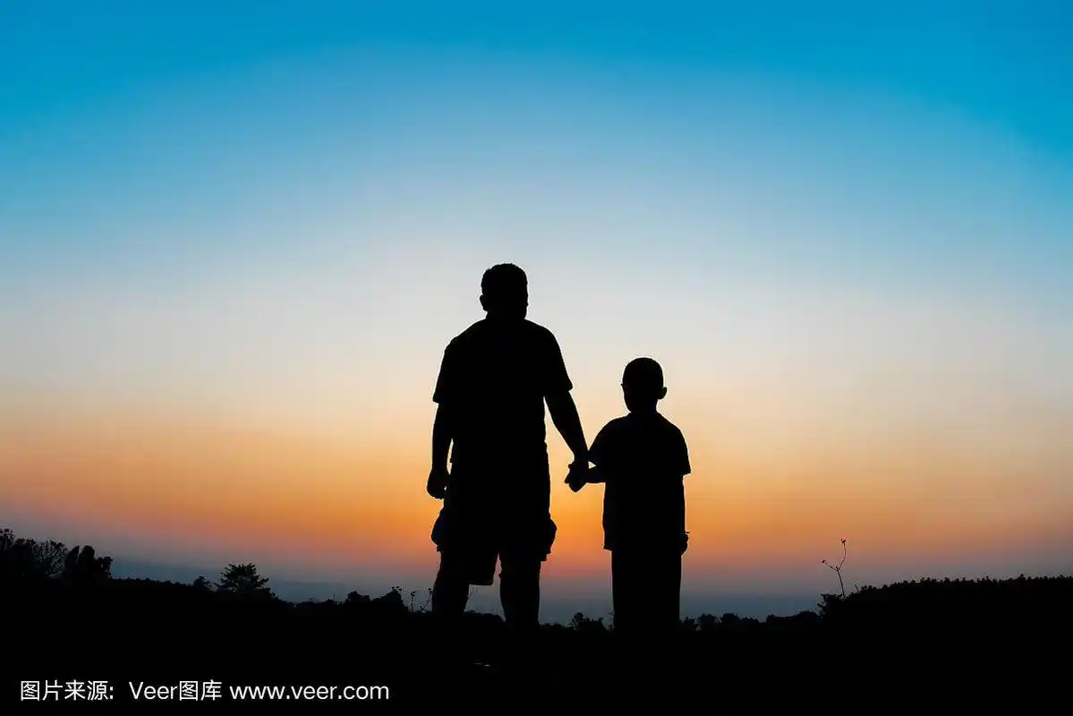 剪影父亲和儿子牵手在傍晚的时间