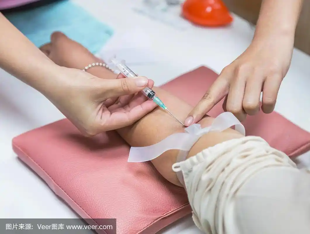 护士在病人手臂上注射针头采血