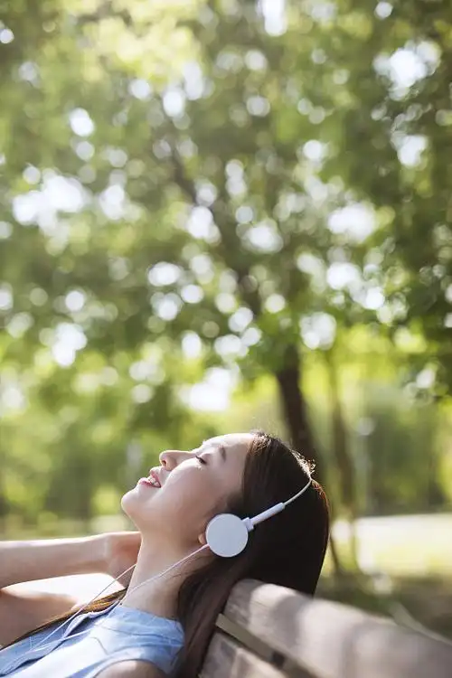 躺在草地上听歌的年轻女孩
