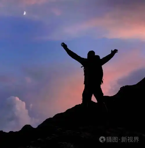 徒步旅行者的剪影,他们的手臂在日落的山顶上