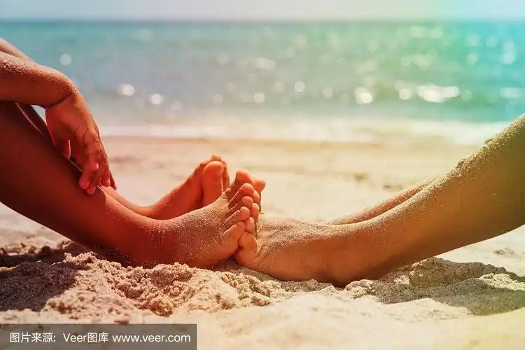 小男孩和小女孩的脚在沙滩上玩沙子