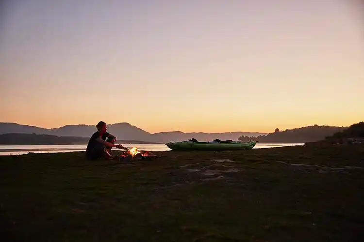 智利,塔尔卡,莫尔河,妇女坐在独木舟旁的篝火旁图片