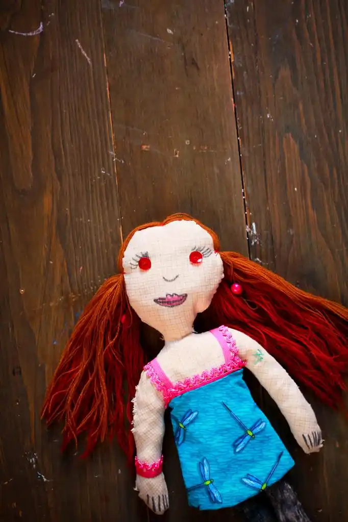 手工制作玩偶,在一个木制的背景上的红头发的手工娃娃