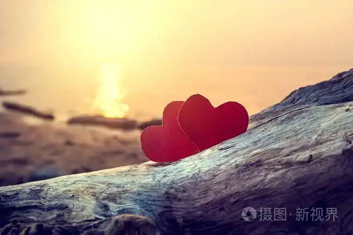两颗红色的心在傍晚的海滩色调的照片
