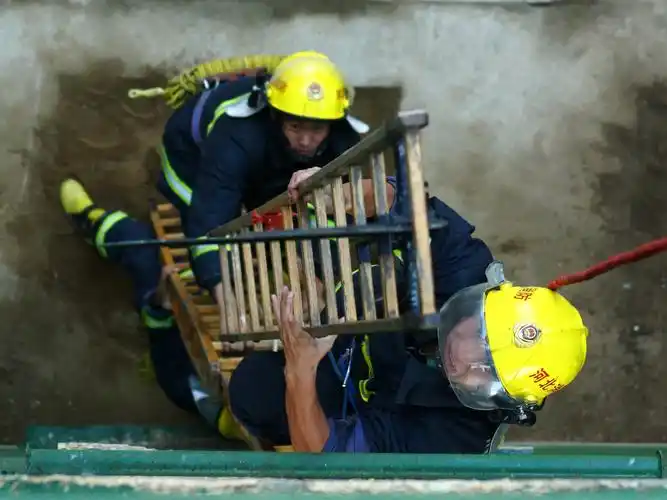 图为:消防战士进行三人配合攀爬3楼挂钩梯训练.