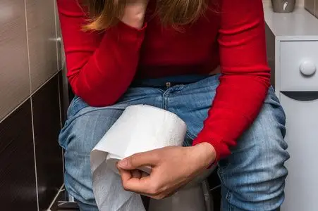 女人在厕所里-腹泻概念拿卫生纸卷照片