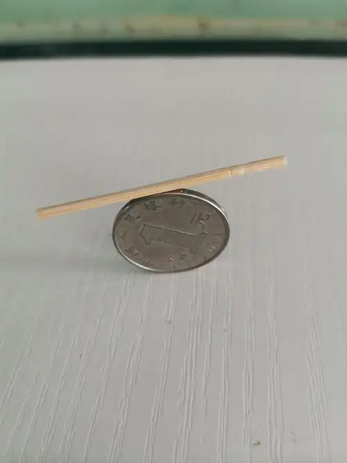 第一步:把硬币竖立在桌子上,牙签放到硬币上.