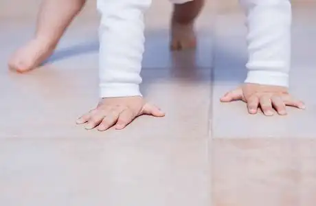 婴儿里程碑概念可爱的金发宝宝爬行的内衣在白色毯子上爬行的小婴儿